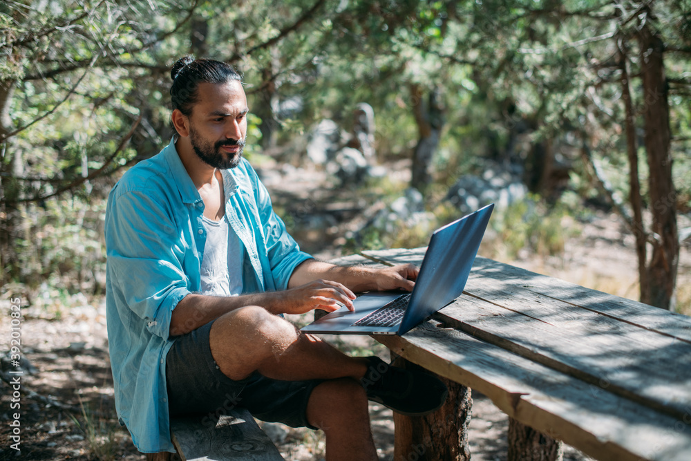 Obraz premium Male tourist working on a laptop outdoors in a camping.