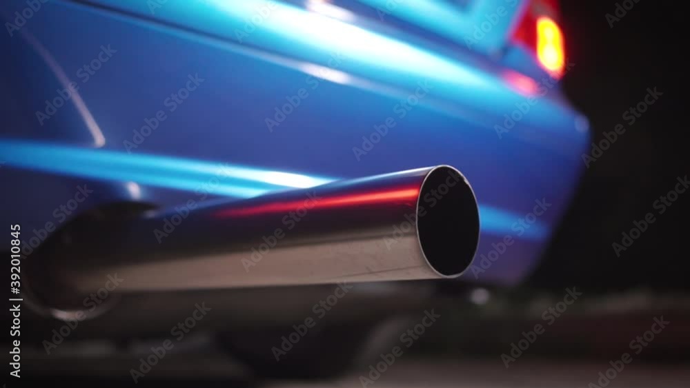 Close up of the exhaust pipe of a tuned sports car. Footage. Part symbol and conceptual tuning, motorsport, workshops, background. Vehicle standing on an asphalt road on a clear weather. Close up of the exhaust pipe of a tuned sports car. Footage. Part symbol and conceptual tuning, motorsport, workshops, background. Vehicle standing on an asphalt road on a clear weather.