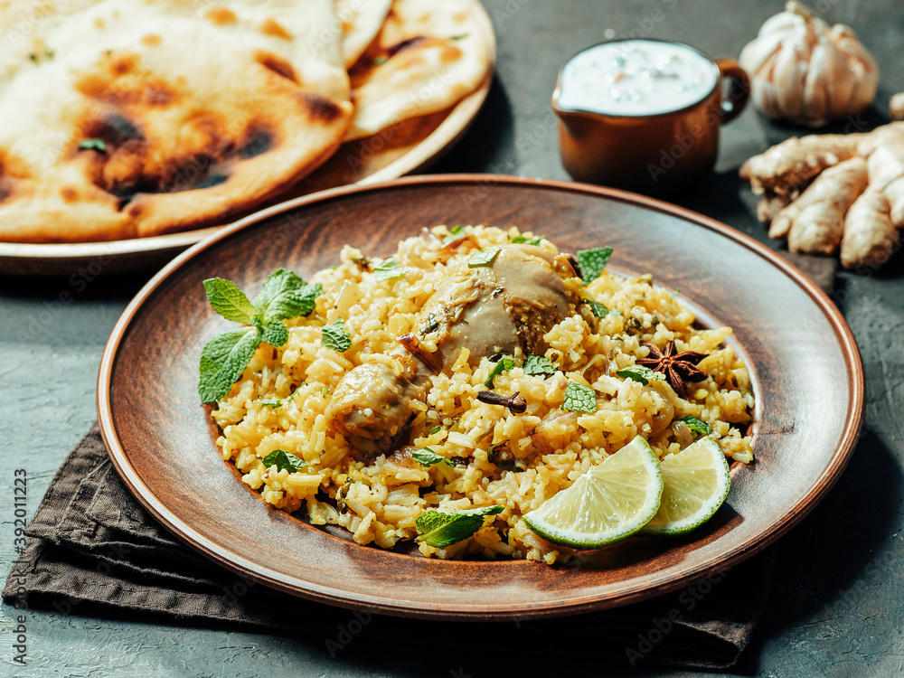 Pakistani food - biryani rice with chicken, raita yoghurt dip and naan flat bread. Delicious hyberabadi chicken biryani on black background Pakistani food - biryani rice with chicken, raita yoghurt dip and naan flat bread. Delicious hyberabadi chicken biryani on black background
