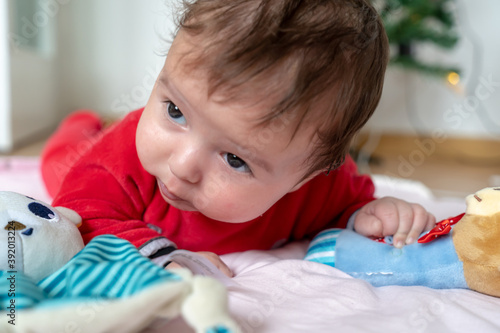 Closeup portrait of newborn baby. baby in Santa costume lying around the bright lights at the Christmas tree in new year's eve