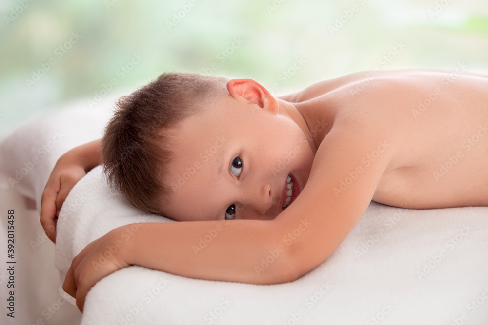 Happy boy lying on a massage table waiting for massage Happy boy lying on a massage table waiting for massage