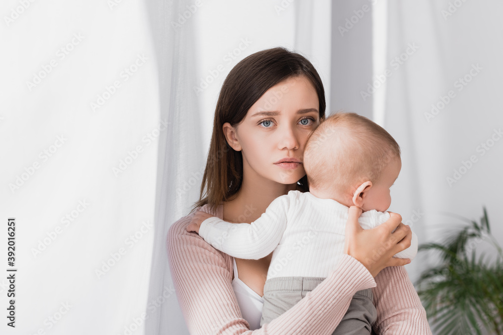 worried mother holding in arms baby boy and looking at camera worried mother holding in arms baby boy and looking at camera