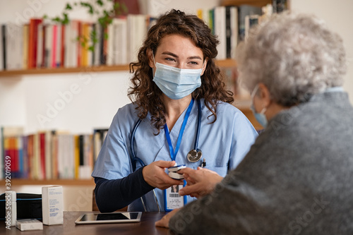 Canvas Print Doctor examining senior woman using oximeter at home