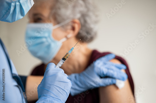 Doctor makes vaccination to senior woman with surgical mask