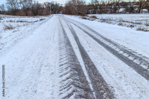 Tire tracks on icy road covered with snow © olyasolodenko