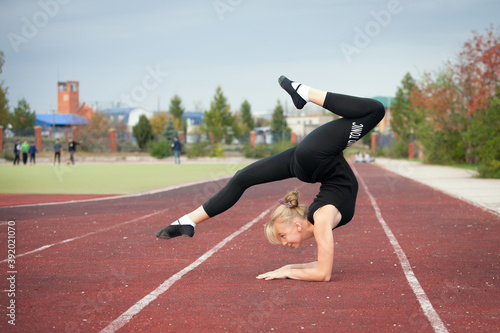 Sports teenage girl in the stadium performs gymnastic exercises