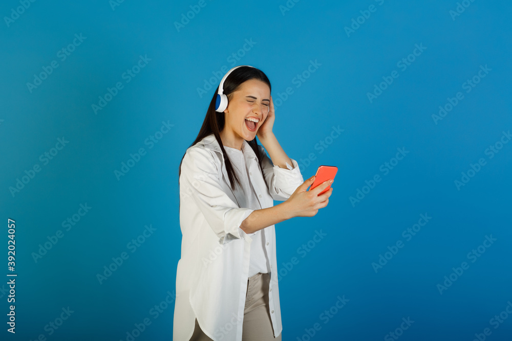 Excited woman with closed eyes wearing headphones using phone and cellphone while listen favorite song. Excited woman with closed eyes wearing headphones using phone and cellphone while listen favorite song.