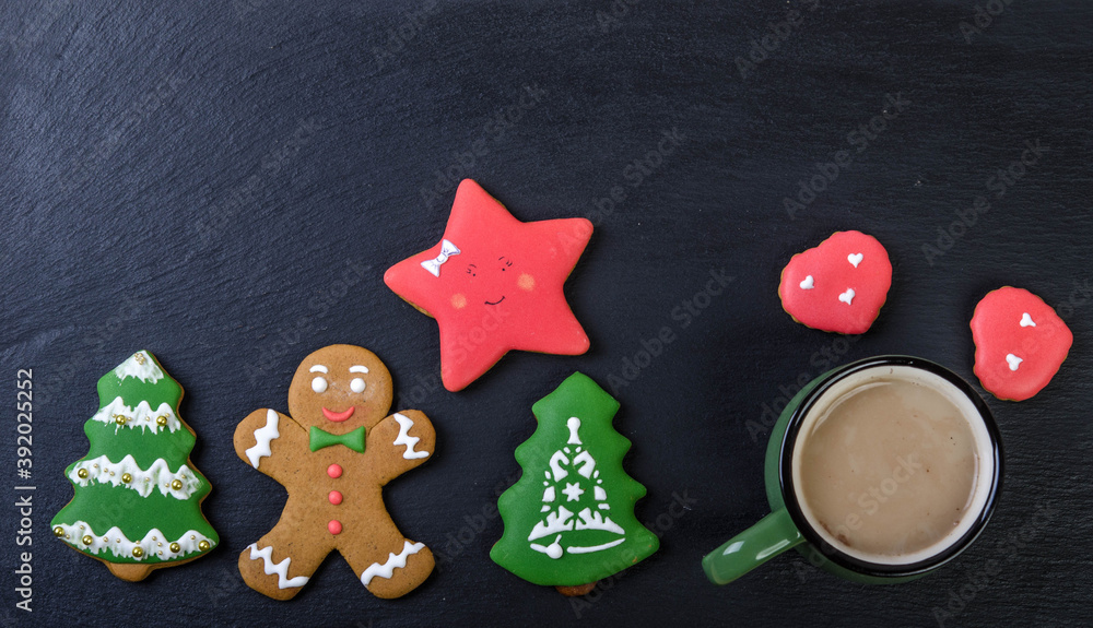 Gingerbread cookies and a mug with cocoa on a black background.