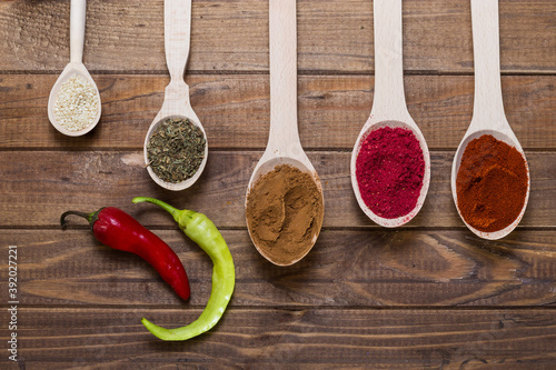 Spices in spoons on wooden table with hop