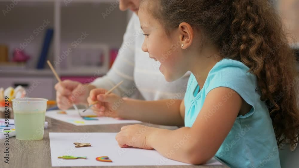 family, motherhood and leisure concept - mother spending time with her little daughter drawing with colors at home family, motherhood and leisure concept - mother spending time with her little daughter drawing with colors at home