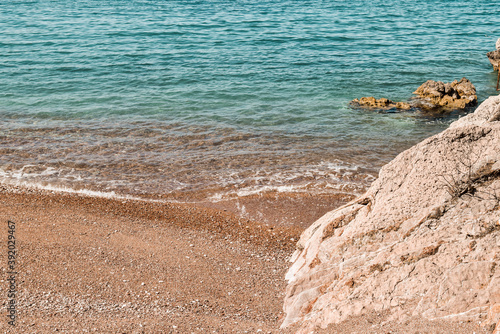 Rocks, blue sea and swash coming onto the gravel beach. © marisa
