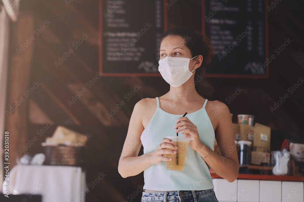 Young woman in protective mask buying food and beverage in cafe to takeaway