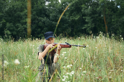 Woman woman aiming aside while sitting on the ground on nature weapons green trees 
