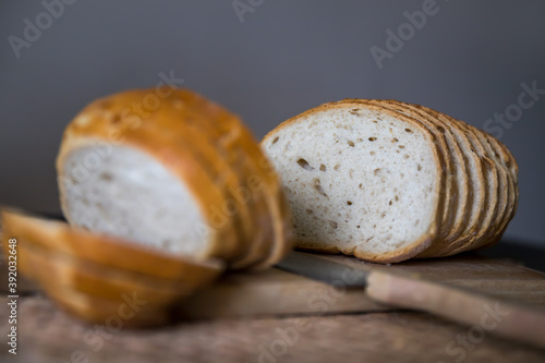 Krojony chleb na desce na szarym tle z nożem