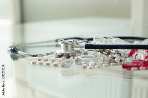 Stethoscope pills ampoules and tablets on glass table