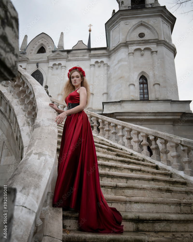 Girl in a red dress on the steps of a gothic temple