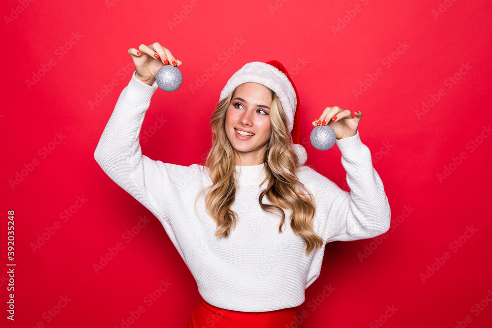 Φωτογραφία Beautiful young woman wearing Santa's holding Christmas tree toys isolated on re