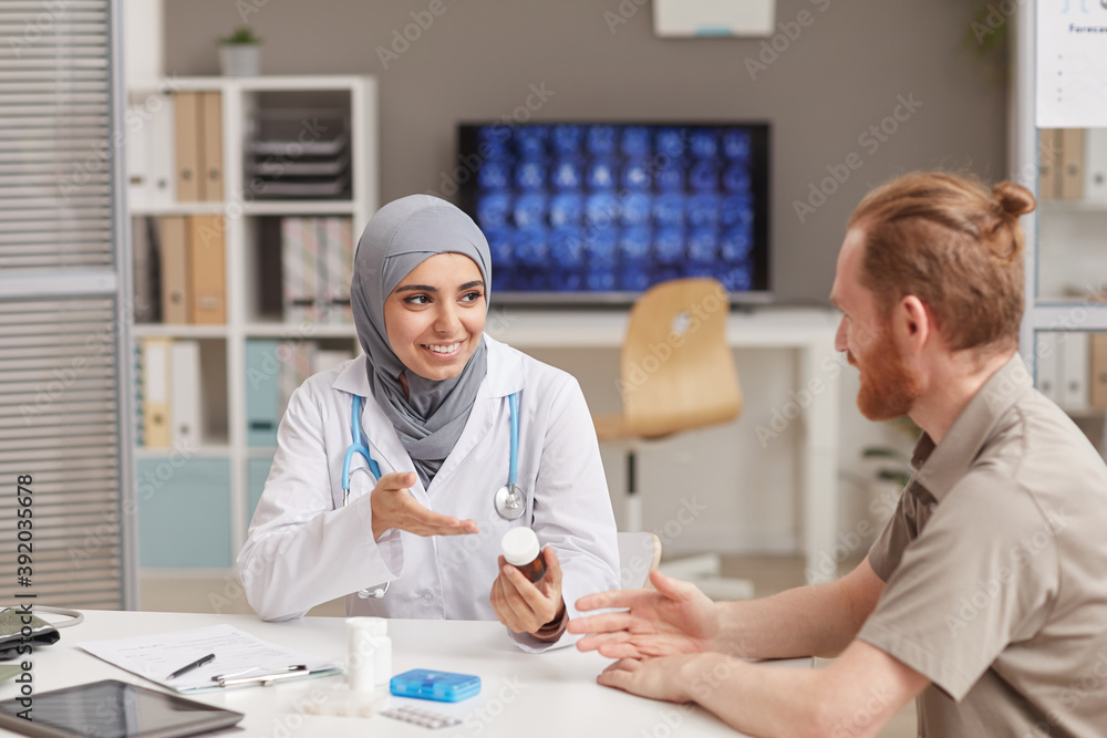 Obraz premium Muslim female doctor telling about the medicine to her patient during his visit at hospital