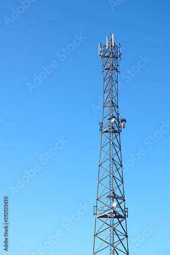 Telecommunication tower of 3G, 4G and 5G cellular network against the blue sky.