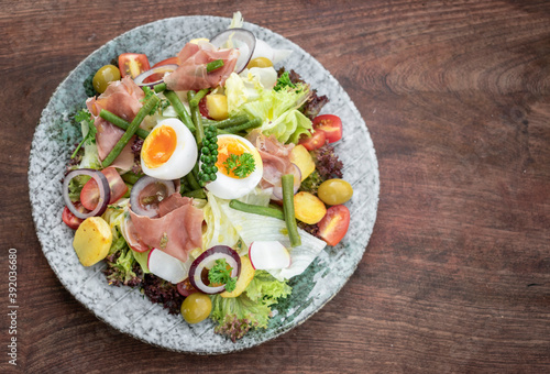 nicoise style healthy organic salad with egg and ham outdoors
