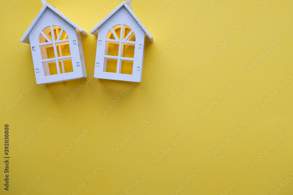 Glowing wooden houses garlands on a yellow background. New year and christmas concept, real estate concept