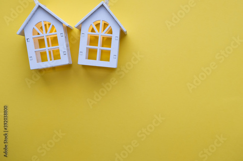 Obraz na płótnie Glowing wooden houses garlands on a yellow background. New year and christmas concept, real estate concept w salonie