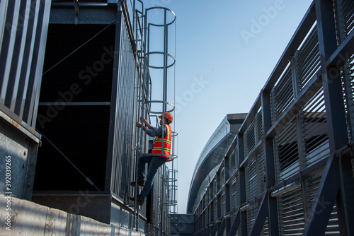 construction workers on a site. engineer under checking the industry cooling tower air conditioner is water cooling tower air chiller HVAC of large industrial building to control air system.