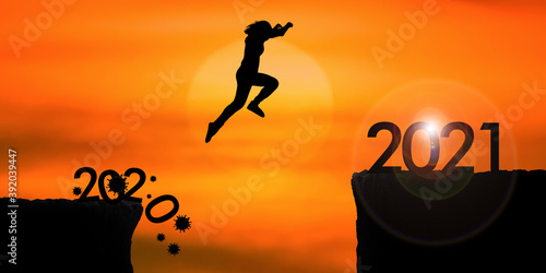 Silhouette woman jumping from 2020 cliff to 2021 cliff on sunrise time