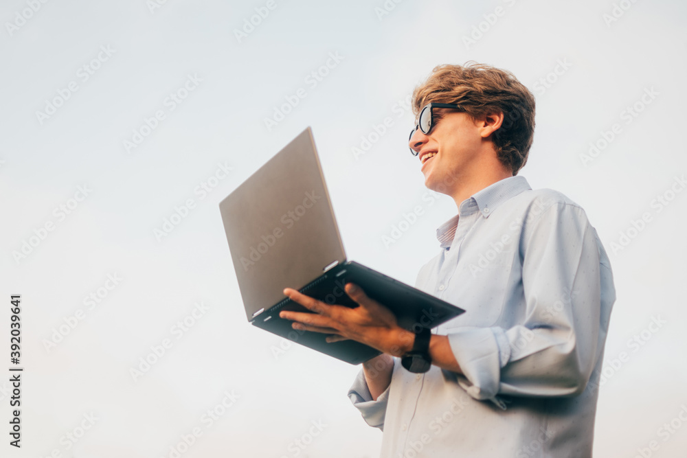 Young businessman standing up using laptop Young businessman standing up using laptop