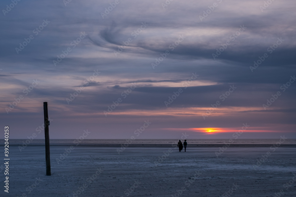 Two people on the beach at sunset