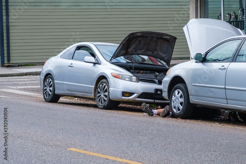 Legs showing of person working on car with mechanical problems on street