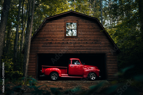 Antique rustic 1950's red truck in a wooden log barn in the woods