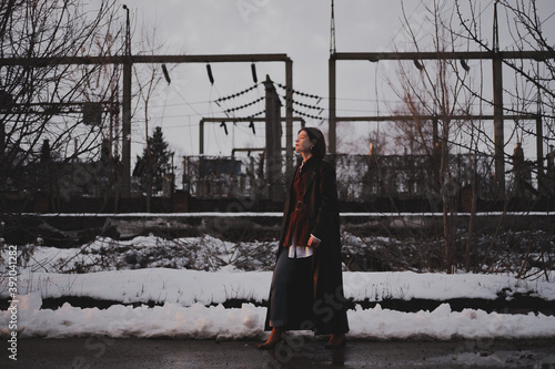 Woman in leather coat walks in industrial area in winter, low ke photo