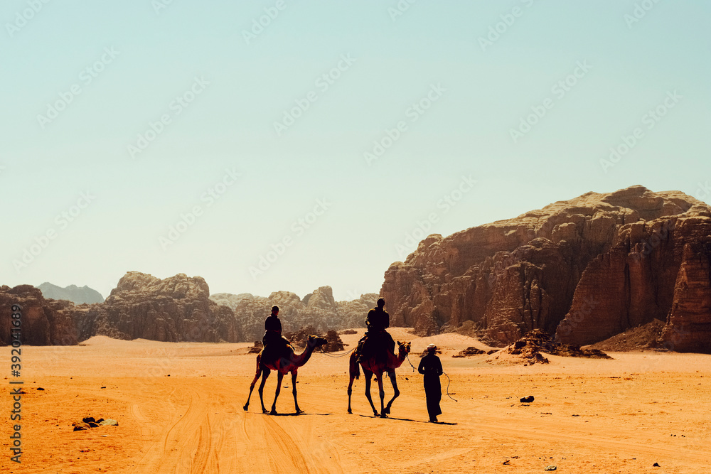 Tourists ride camels with a Bedouin guide in Wadi Rum, Jordan Tourists ride camels with a Bedouin guide in Wadi Rum, Jordan