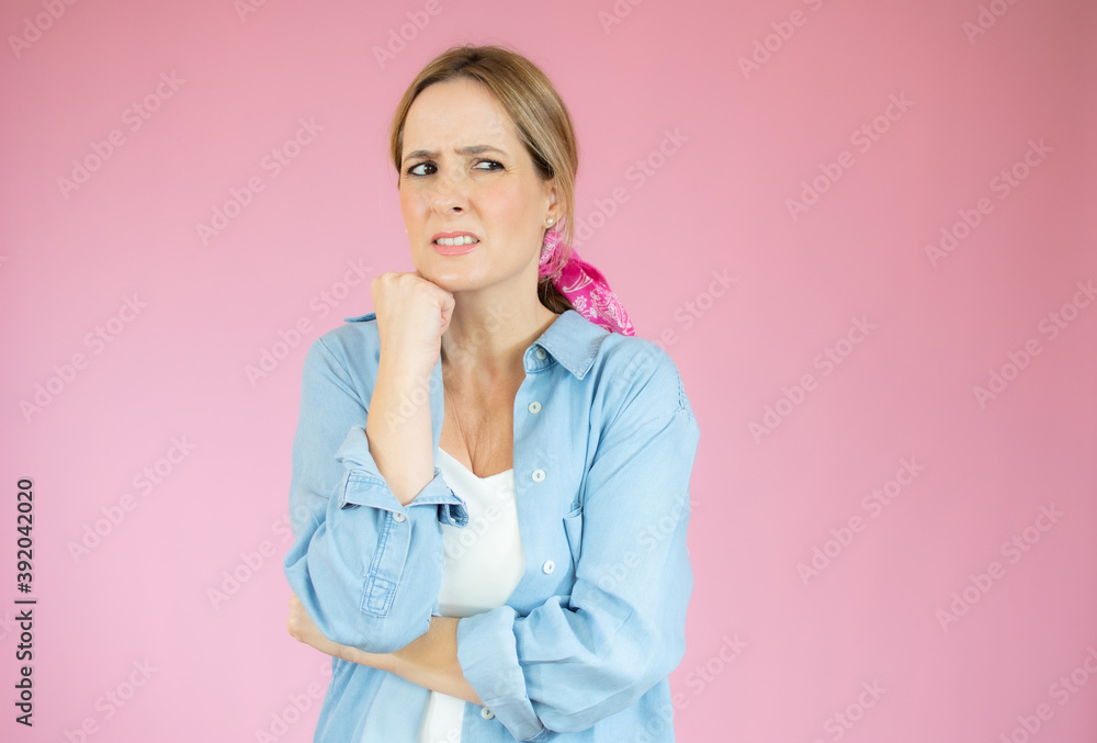 Young beautiful woman wearing denim shirt over pink isolated background Thinking worried about a question, concerned and nervous with hand on chin Young beautiful woman wearing denim shirt over pink isolated background Thinking worried about a question, concerned and nervous with hand on chin