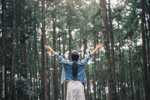 cheering woman open arms to hug the nature. Young woman meditating with open arms standing in fresh spring greenery with her head raised to the sky . beautiful young woman in the forest.