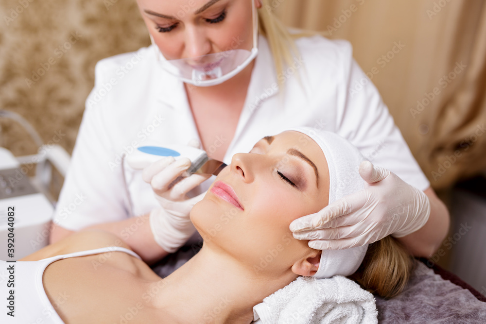 cosmetology and beauty concept - young woman getting facial oxygen anti-aging procedure in beauty salon