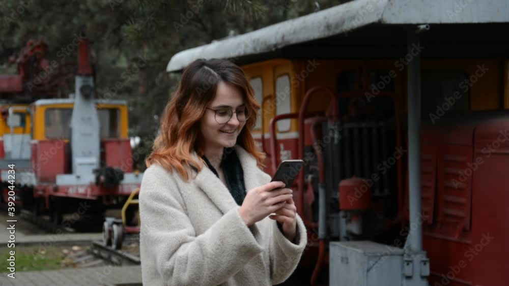 Young girl with glasses writes a message at the railway station Young girl with glasses writes a message at the railway station