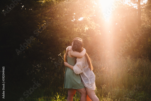 Lesbian couple embracing in forest during summer