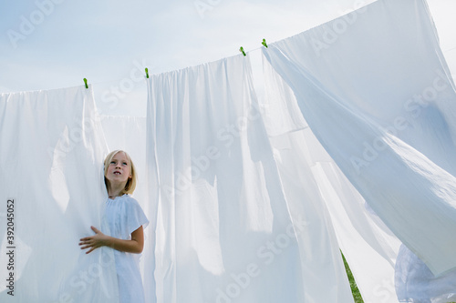 little girl with blond hair in summer hangs up washed clothes