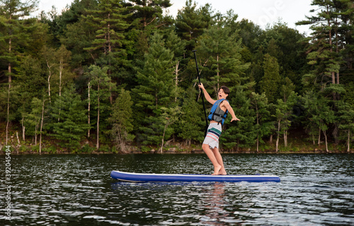 Teen boy falling off of a stand up paddle board (SUP) on a lake. photo