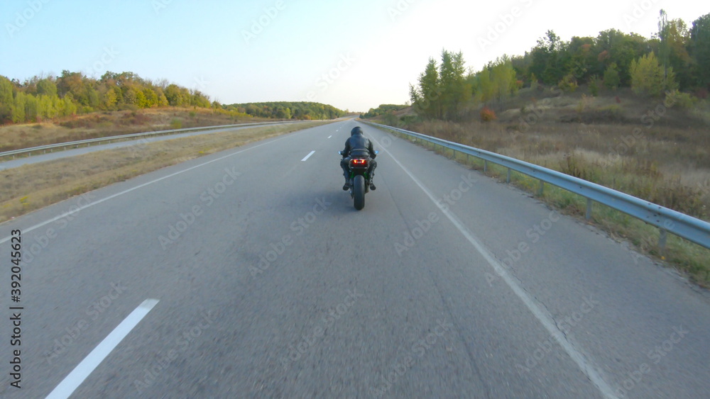 Camera moving around of biker riding on modern sport motorbike at highway. Motorcyclist racing his motorcycle on country road at sunset. Man driving bike during trip. Concept of freedom and adventure Camera moving around of biker riding on modern sport motorbike at highway. Motorcyclist racing his motorcycle on country road at sunset. Man driving bike during trip. Concept of freedom and adventure