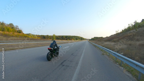 Follow to motorcyclist riding on modern sport motorbike at highway. Biker racing his motorcycle on country road. Guy driving bike during trip. Concept of freedom and adventure at journey. Aerial shot