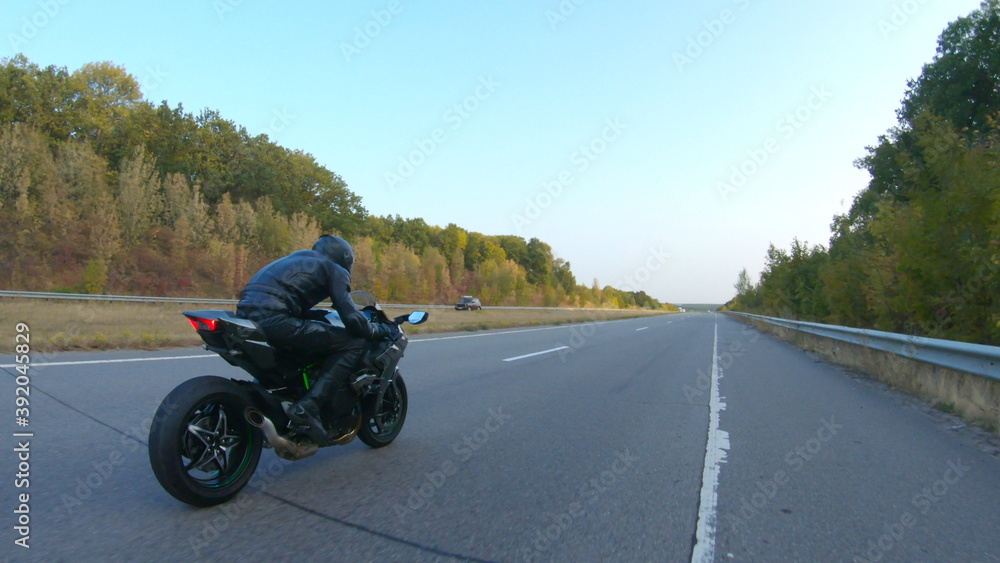Follow to biker riding on modern sport motorbike at autumn highway. Motorcyclist racing his motorcycle on country road. Man driving bike during trip. Concept of freedom and adventure. Aerial shot