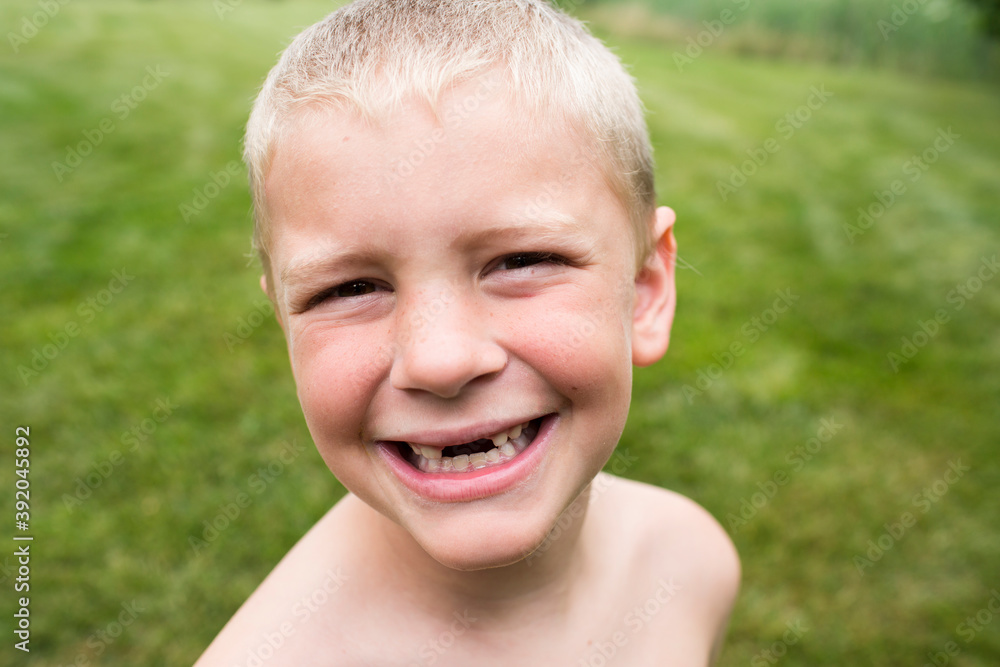 Close Up of Smiling Toothless Young Boy With a Buzz Cut in Backyard Close Up of Smiling Toothless Young Boy With a Buzz Cut in Backyard