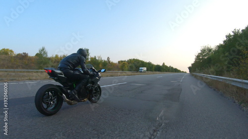 Follow to motorcyclist riding on modern sport motorbike at highway. Biker racing his motorcycle on country road. Guy driving bike during trip. Concept of freedom and adventure at journey. Aerial shot