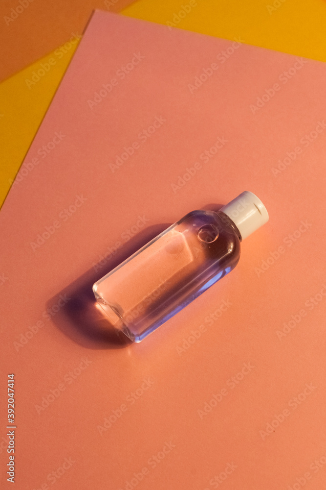 plastic clear transparent bottle without label with antiseptic shampoo shower gel lotion cleanser. yellow and pink flat background plastic clear transparent bottle without label with antiseptic shampoo shower gel lotion cleanser. yellow and pink flat background