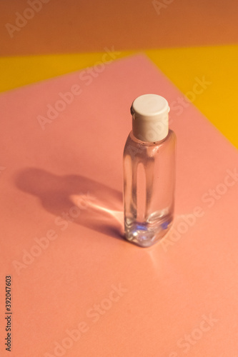 plastic clear transparent bottle without label with antiseptic shampoo shower gel lotion cleanser. yellow and pink flat background