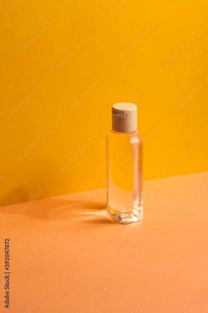 plastic clear transparent bottle without label with antiseptic shampoo shower gel lotion cleanser. yellow and pink flat background