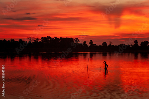 Early morning fisherman setting nets at sunrise in Sra Srang, Siem Reap, Cambodia. Angkorian bathing pool. photo